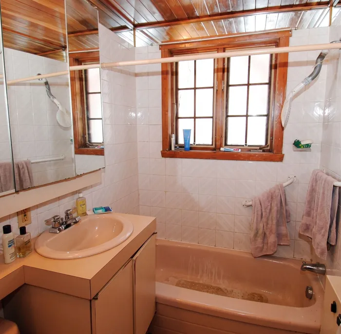 Photo prise pendant la visite : salle de bains ancienne, baignoire et vasque saumon